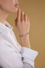 Photo of Young woman with elegant bracelet on beige background, closeup