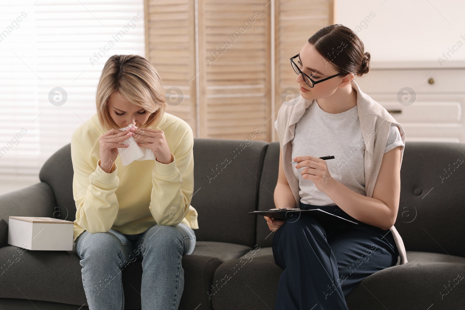 Photo of Professional psychotherapist working with on sofa patient in office