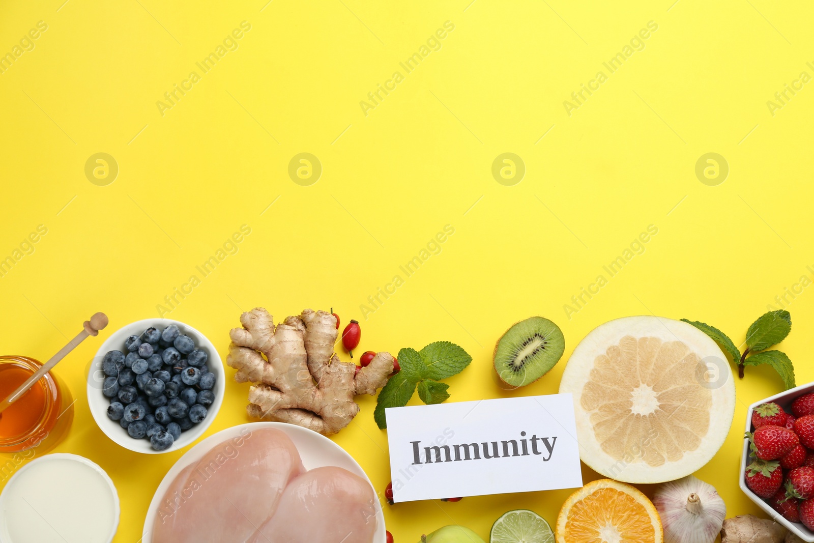 Photo of Set of natural products and card with word Immunity on yellow background, flat lay. Space for text