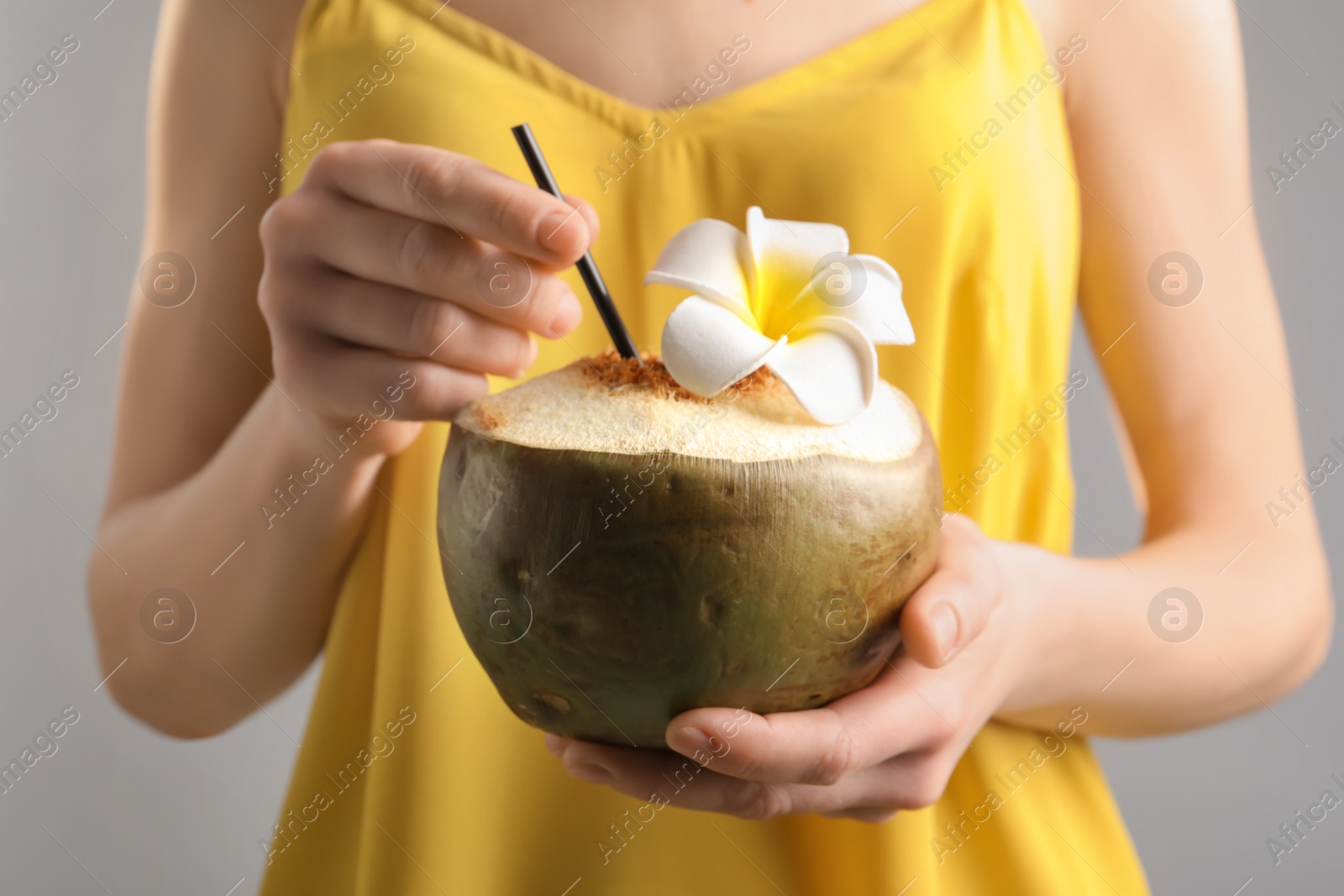 Photo of Young woman with fresh coconut cocktail on blurred background, closeup