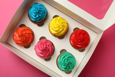 Photo of Box with different cupcakes on pink background, top view