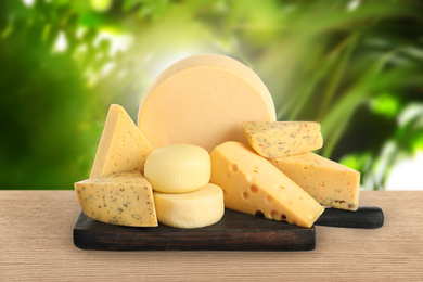 Image of Different types of delicious cheeses on wooden table outdoors. Dairy products