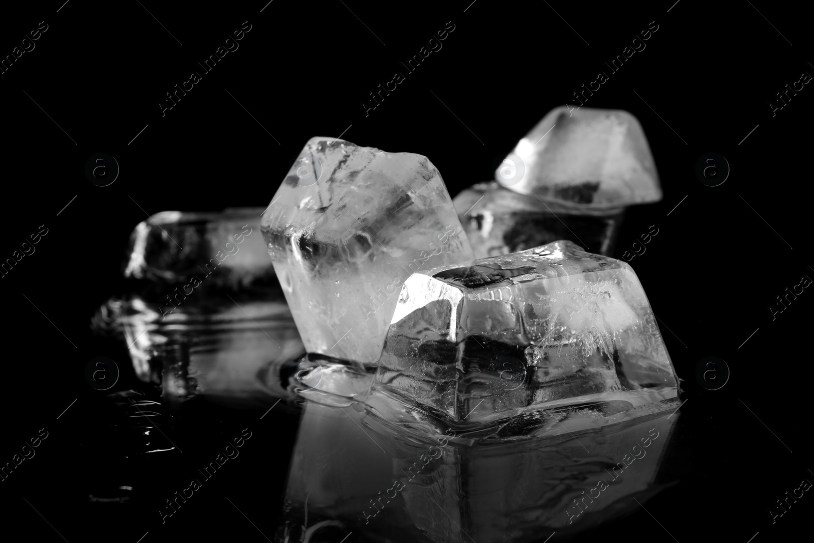 Photo of Transparent ice cubes on black mirror surface