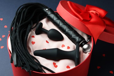 Photo of Gift box with different sex toy on dark blue background
