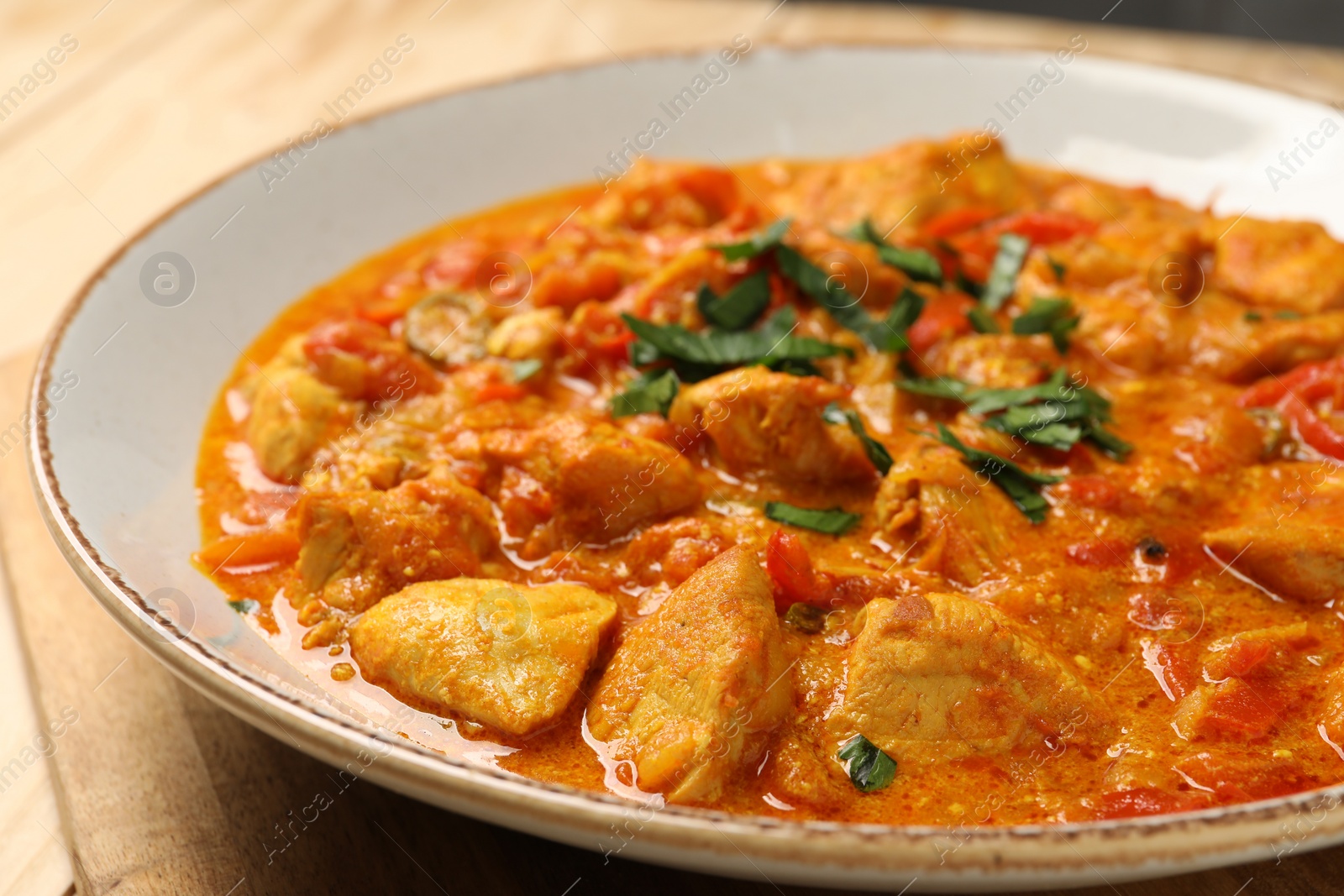 Photo of Delicious chicken curry with parsley on table, closeup