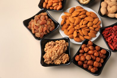 Bowls with dried fruits and nuts on beige background, above view