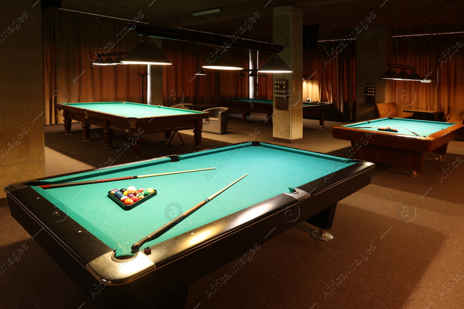 Photo of Billiard tables with balls and cues in club