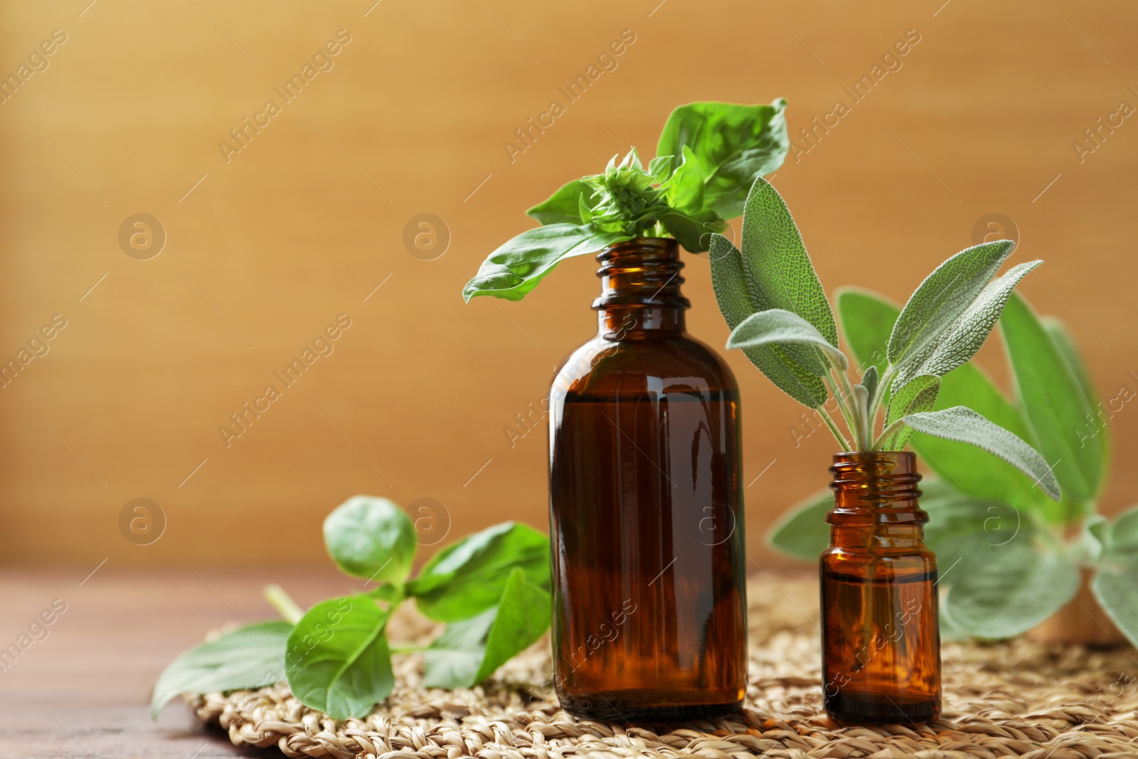 Photo of Bottles of essential oils and fresh herbs on wooden table, space for text