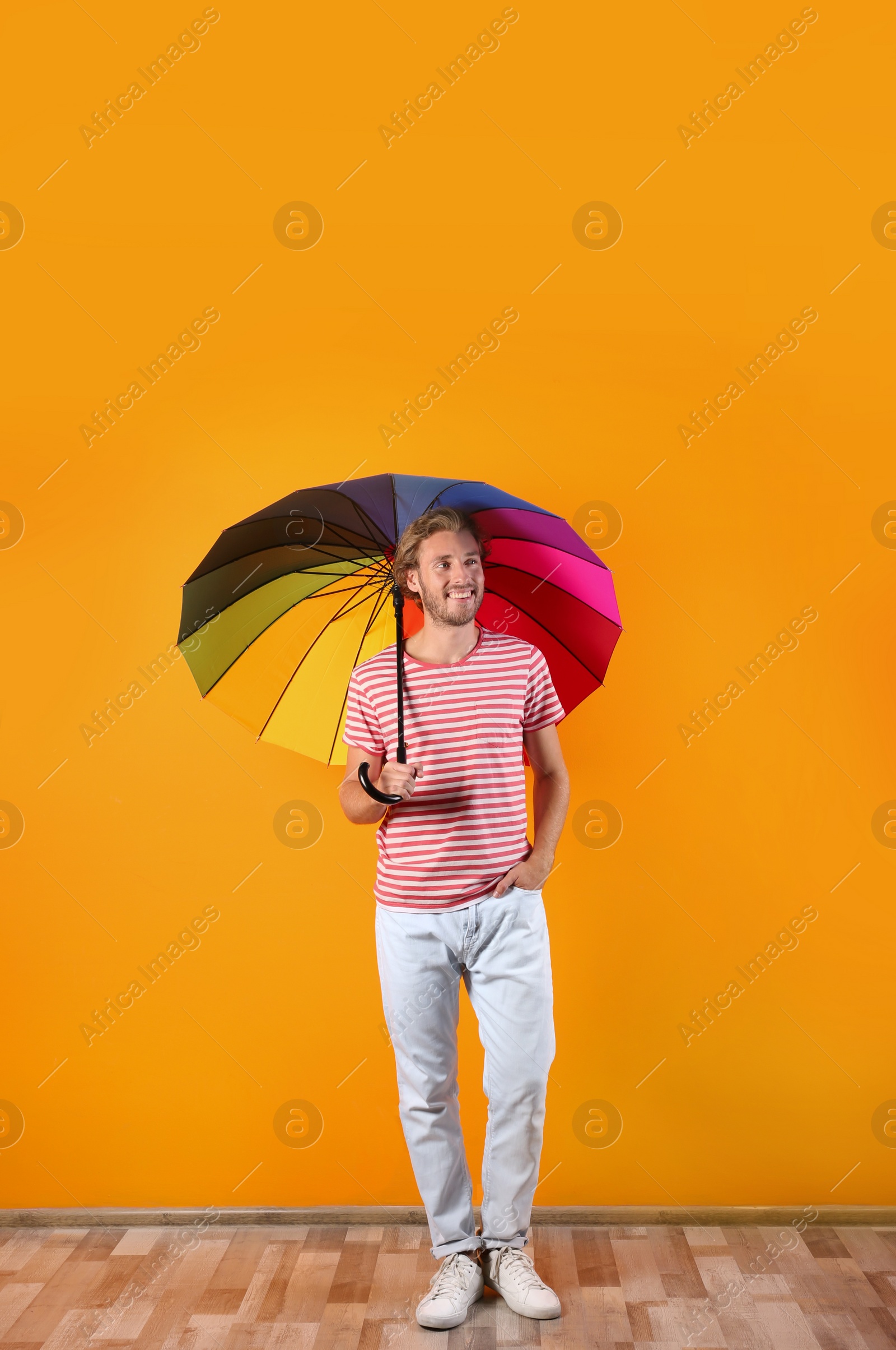 Photo of Man with rainbow umbrella near color wall