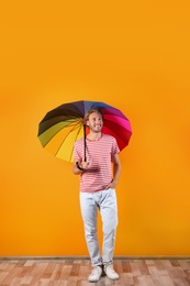 Man with rainbow umbrella near color wall