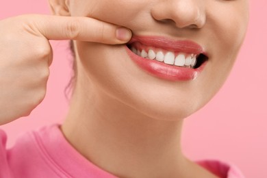 Photo of Beautiful woman showing her clean teeth on pink background, closeup