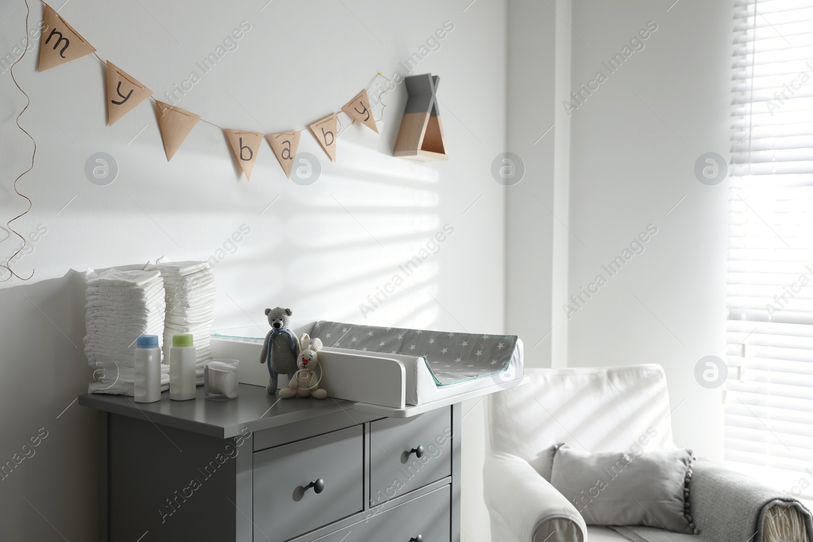 Photo of Chest of drawers with changing tray and pad in baby room. Interior design