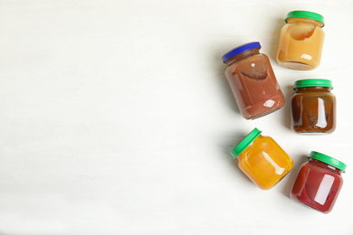 Photo of Jars with baby food on white wooden table, flat lay. Space for text