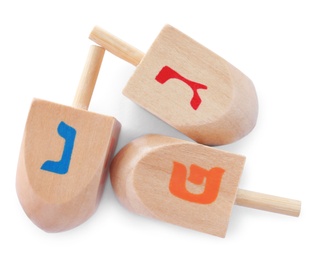 Photo of Wooden Hanukkah traditional dreidels with letters Nun, Gimel and Pe on white background, top view