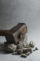 Photo of One sledgehammer and pieces of broken stones on grey background, closeup