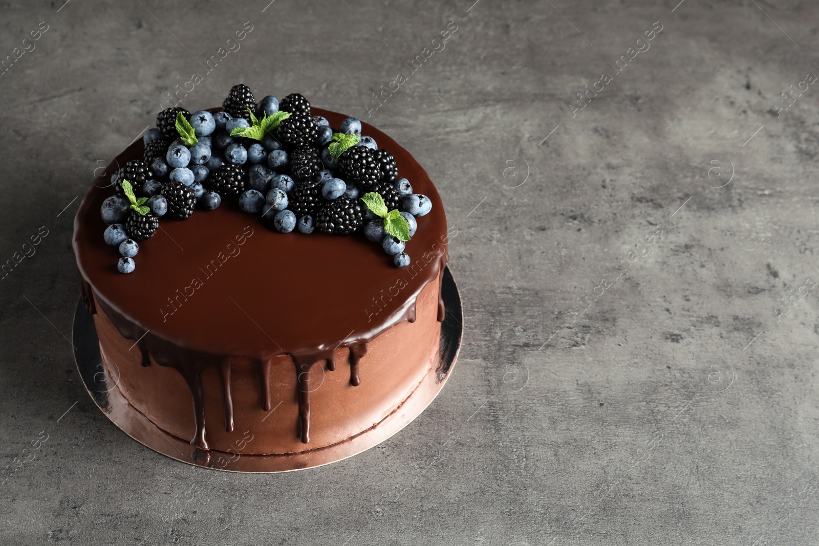 Photo of Fresh delicious homemade chocolate cake with berries on gray table. Space for text