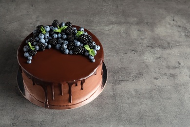 Fresh delicious homemade chocolate cake with berries on gray table. Space for text