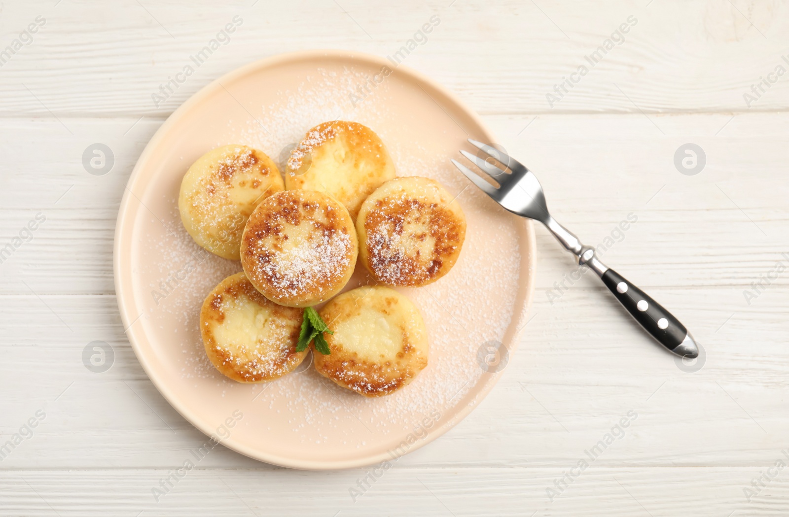 Photo of Delicious cottage cheese pancakes with mint and icing sugar on white wooden table, flat lay