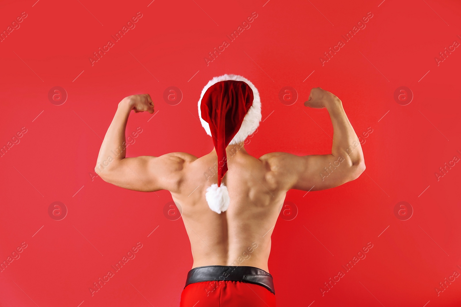 Photo of Young muscular man in Santa hat on color background