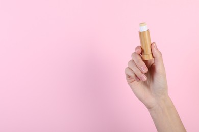 Photo of Woman with lip balm on pink background, closeup. Space for text