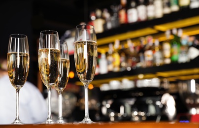 Photo of Glasses of champagne on counter in bar. Space for text