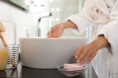 Young woman taking soap bar to wash hands in bathroom, closeup