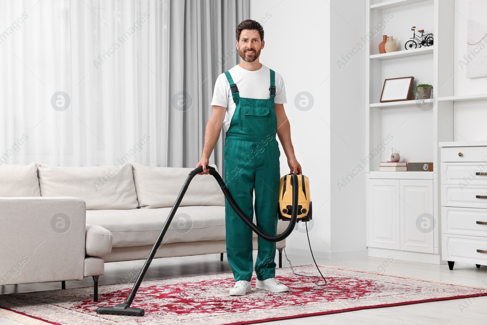 Photo of Dry cleaner's employee hoovering carpet with vacuum cleaner in room