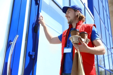 Male courier with order ringing in doorbell at entrance. Food delivery service