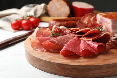 Photo of Cutting board with different meat delicacies on gray table