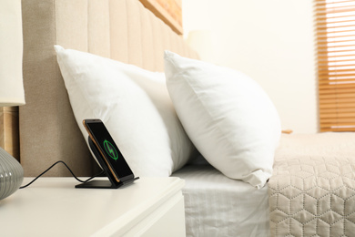 Modern mobile phone charging on wireless pad in bedroom