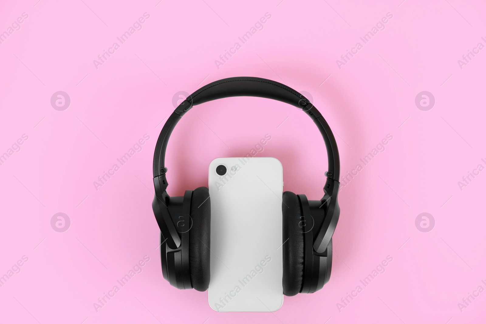 Photo of Modern wireless headphones and smartphone on pink background, top view