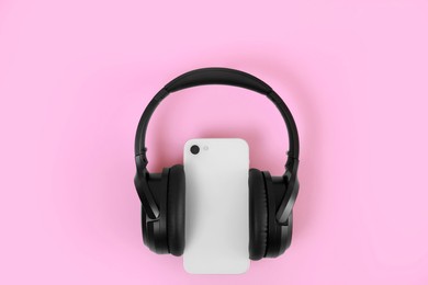 Photo of Modern wireless headphones and smartphone on pink background, top view