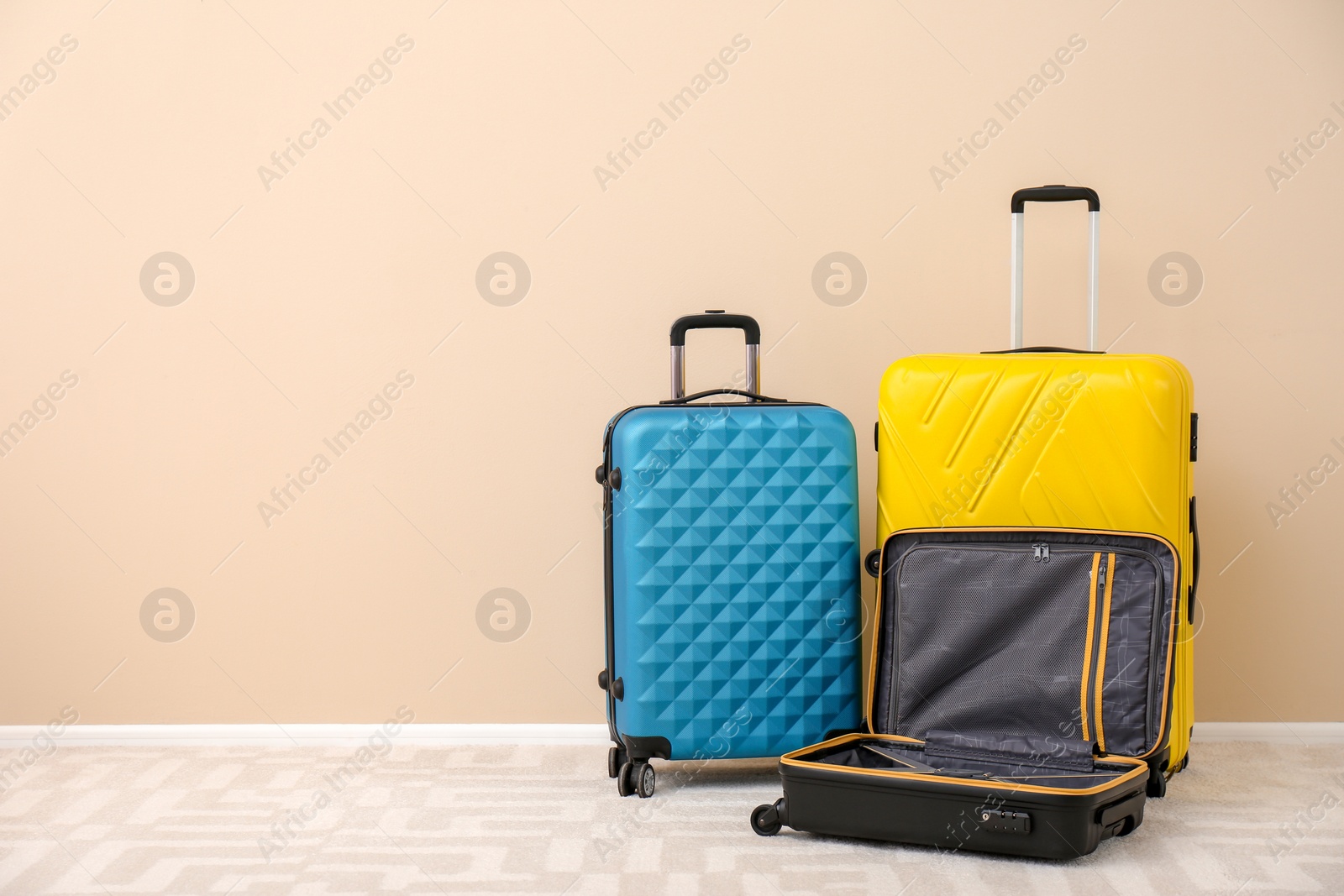 Photo of Modern suitcases on floor near light wall. Space for text