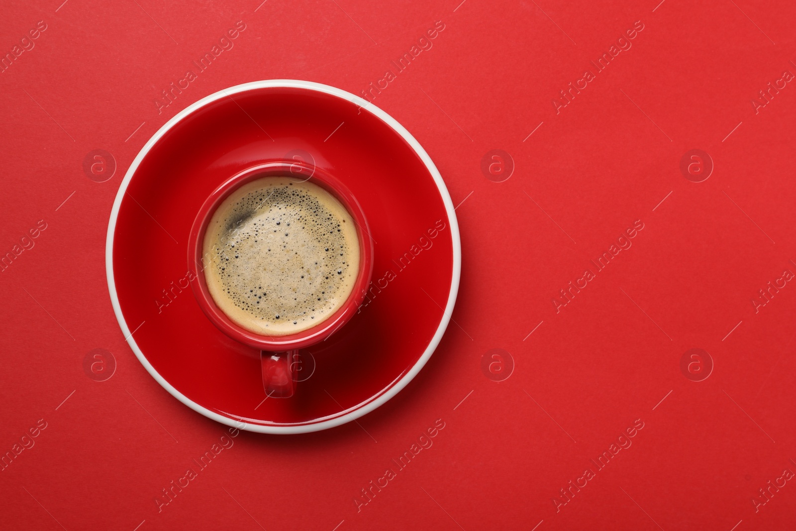 Photo of Tasty coffee in cup on red background, top view. Space for text