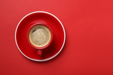 Tasty coffee in cup on red background, top view. Space for text