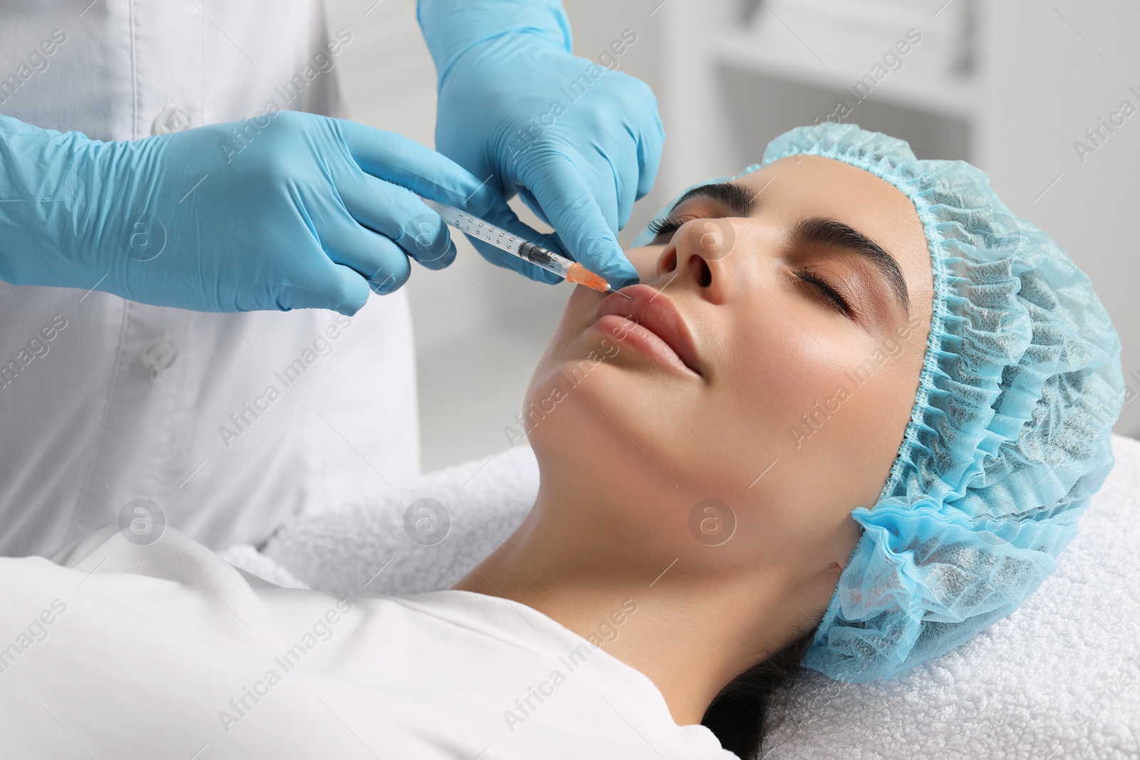 Photo of Doctor giving lips injection to young woman in clinic. Cosmetic surgery