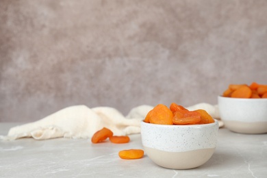 Photo of Bowl with apricots on grey table, space for text. Dried fruit as healthy food