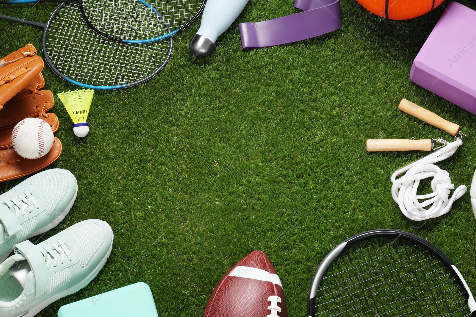 Photo of Frame of different sport tools on green grass, flat lay. Space for text