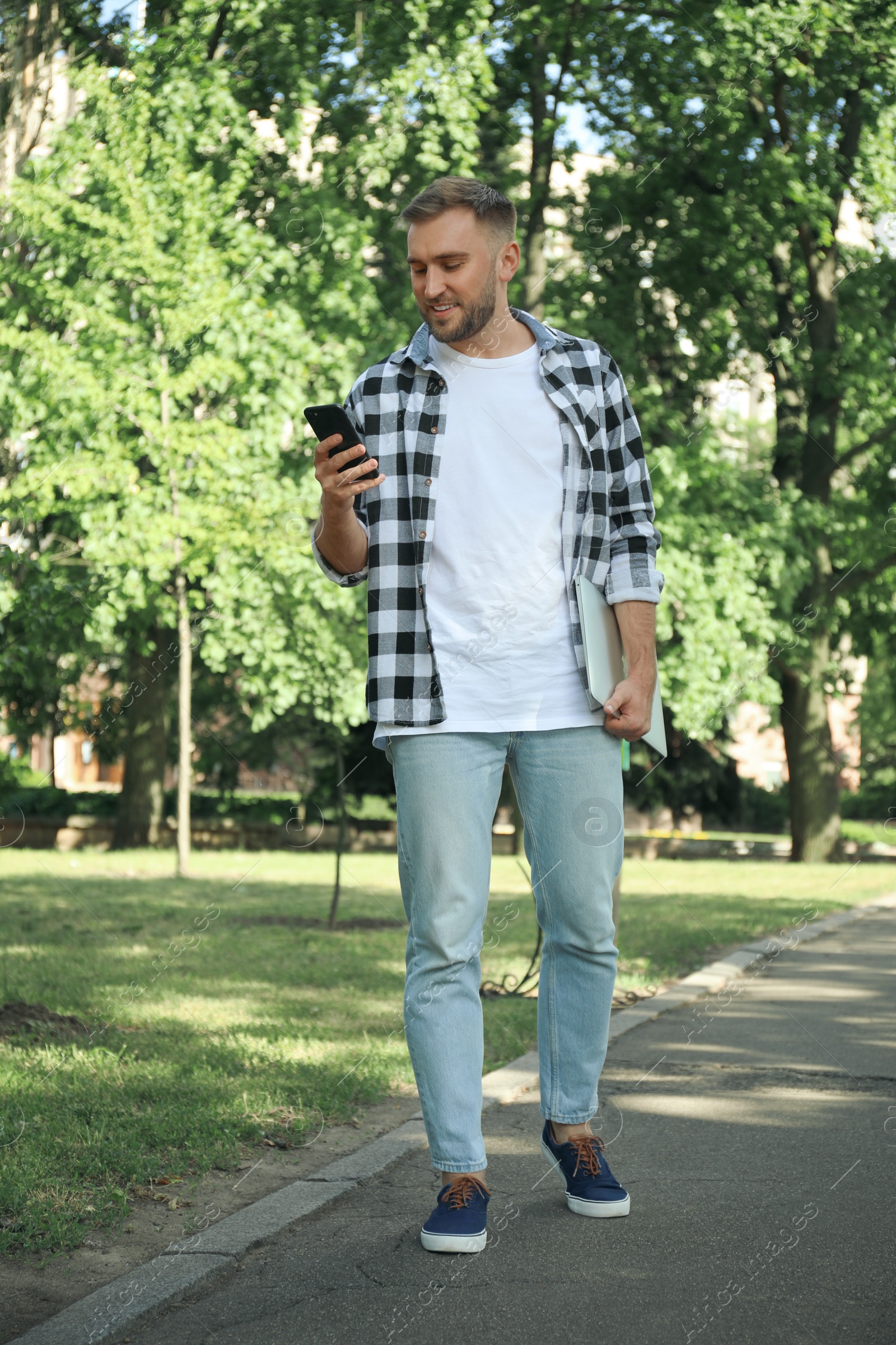 Photo of Young man with smartphone in park on summer day