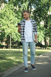 Young man with smartphone in park on summer day