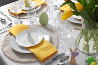 Photo of Festive table setting with glasses and vase of tulips. Easter celebration