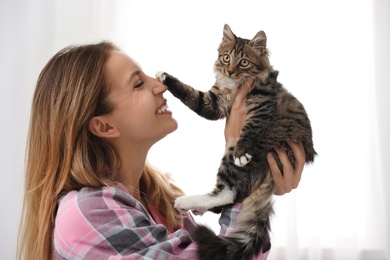 Woman wearing pajama with cat at home. Owner and pet