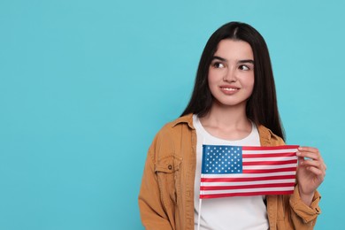 Photo of 4th of July - Independence Day of USA. Happy girl with American flag on light blue background, space for text