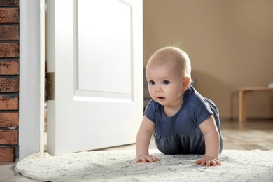 Cute little baby crawling on rug indoors