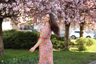 Beautiful woman near blossoming trees on spring day
