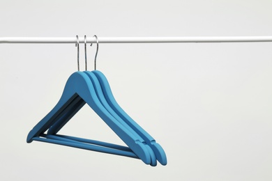 Photo of Empty clothes hangers on metal rail against light background. Space for text