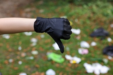 Photo of Woman showing thumb down in park, closeup. Garbage collection