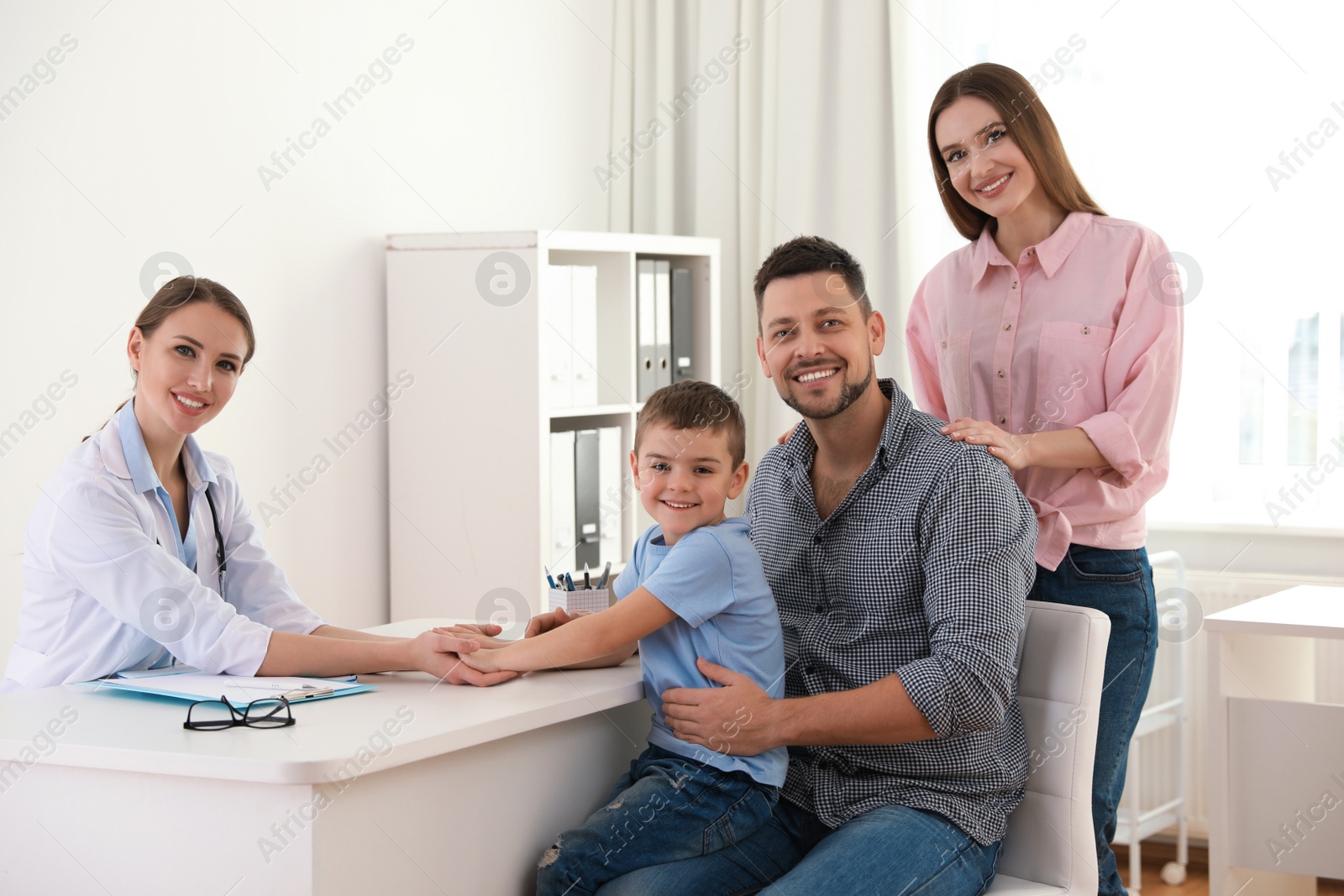 Photo of Parents and son visiting pediatrician. Doctor working with patient in hospital