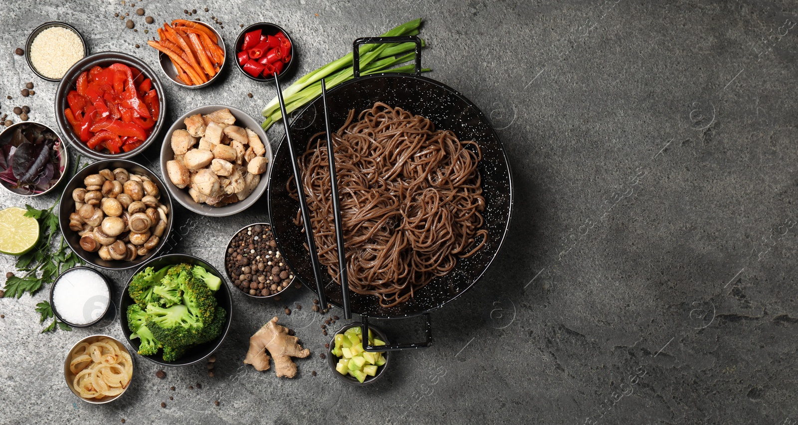 Photo of Wok with noodles, chicken and other products on grey table, flat lay. Space for text