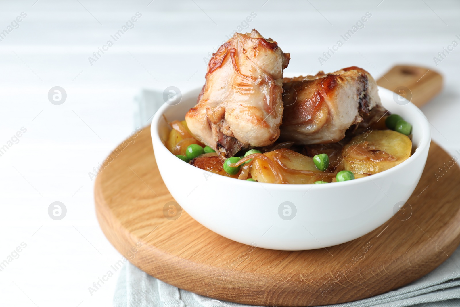 Photo of Tasty cooked rabbit with vegetables in bowl on white table, closeup. Space for text